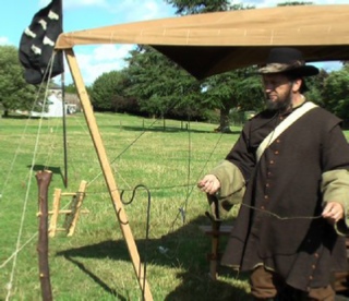 Ian making turning nettle string into rope using a hand-made wink